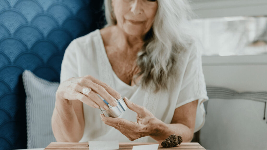 older woman using grinder for cannabis buds