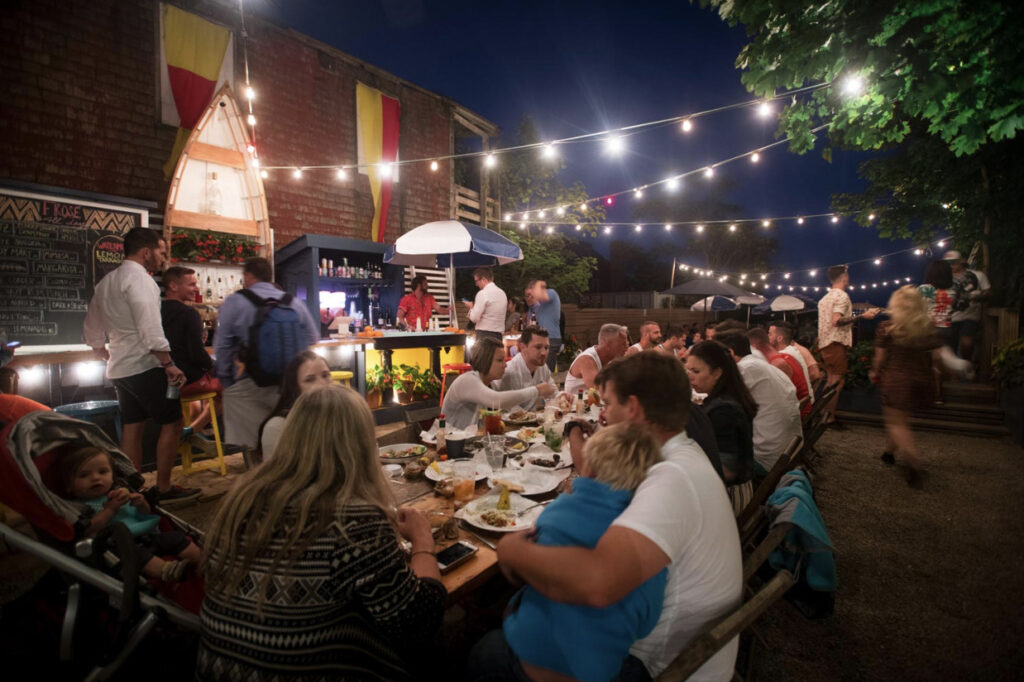 People gathered around an outdoor table eating. 
